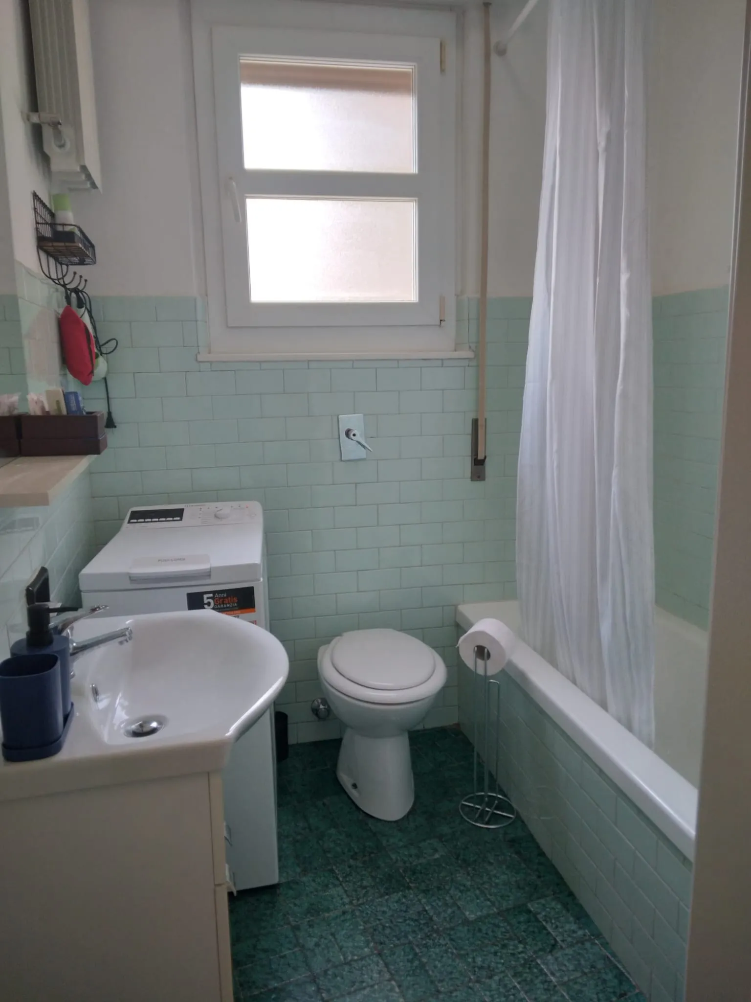 La salle de bains, avec baignoire, fenêtre et lave-linge