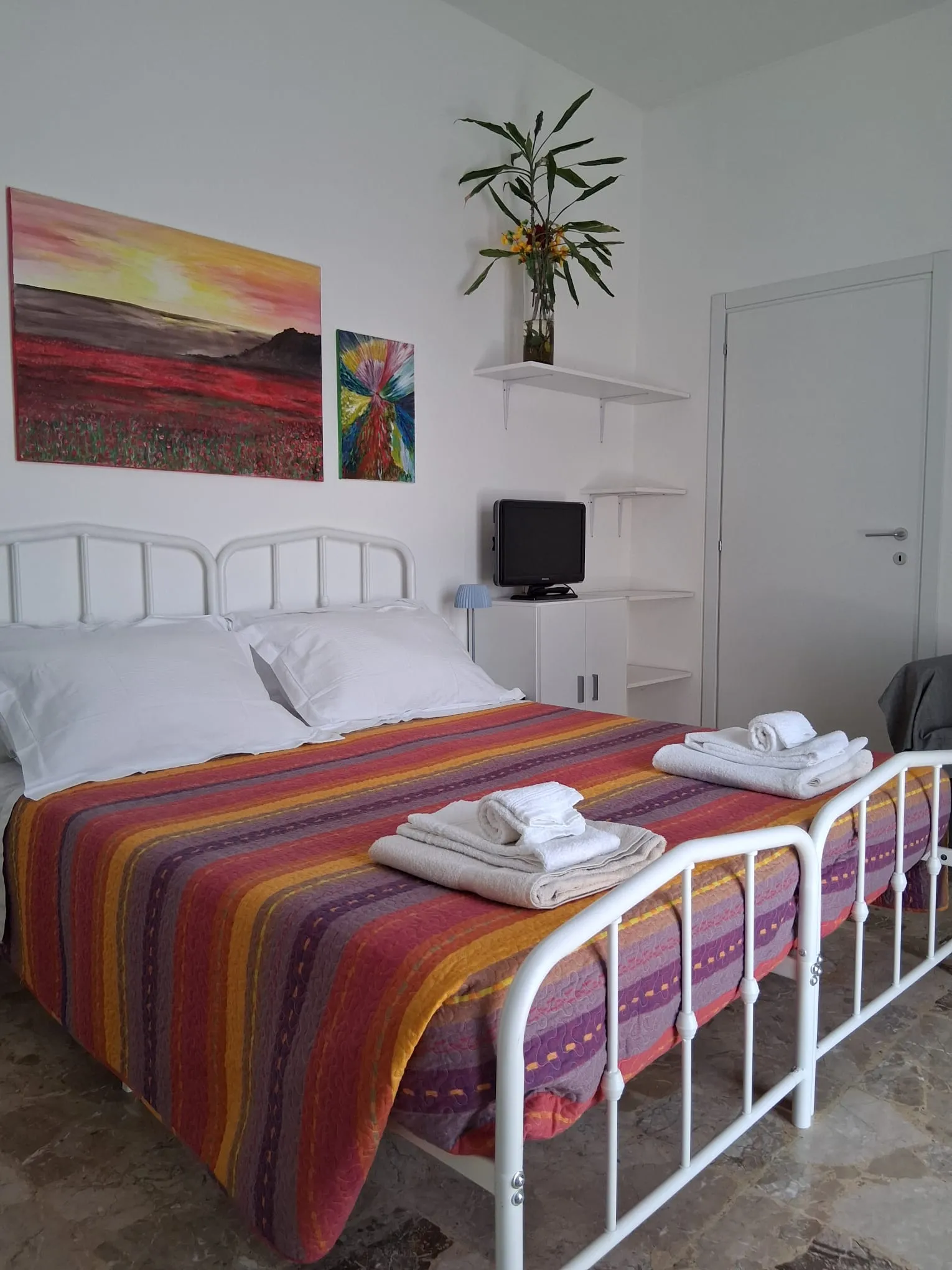 Le lit double avec des serviettes propres, sous un tableau coloré