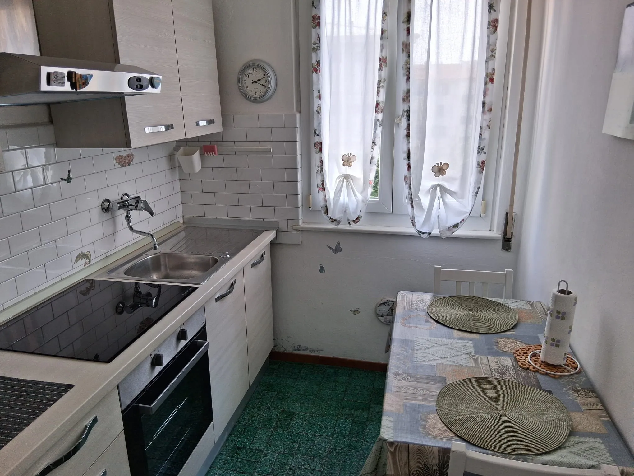 La cuisine séparée, avec plaque à induction, four et une table pour deux